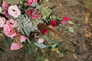 Ein Strauß Blumen mit roten und rosafarbenen Rosen. Dazwischen sind ein paar grüne Zweige zu Dekoration. Der Strauß steht auf einem steinigen Untergrund.